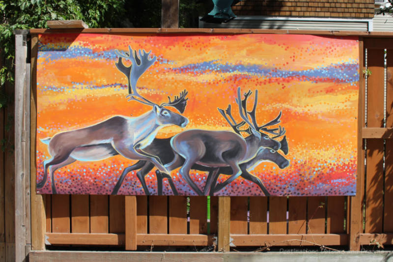 Painting of caribou running against orange background on garage in Artic Alley, Winnipeg