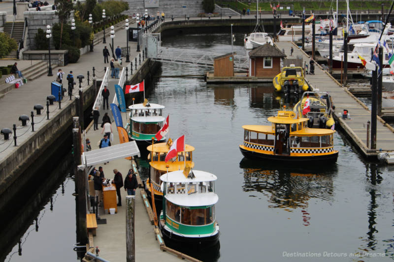 Yellow and green pickle-shaped boats of Victoria Harbour Ferry moored at marina