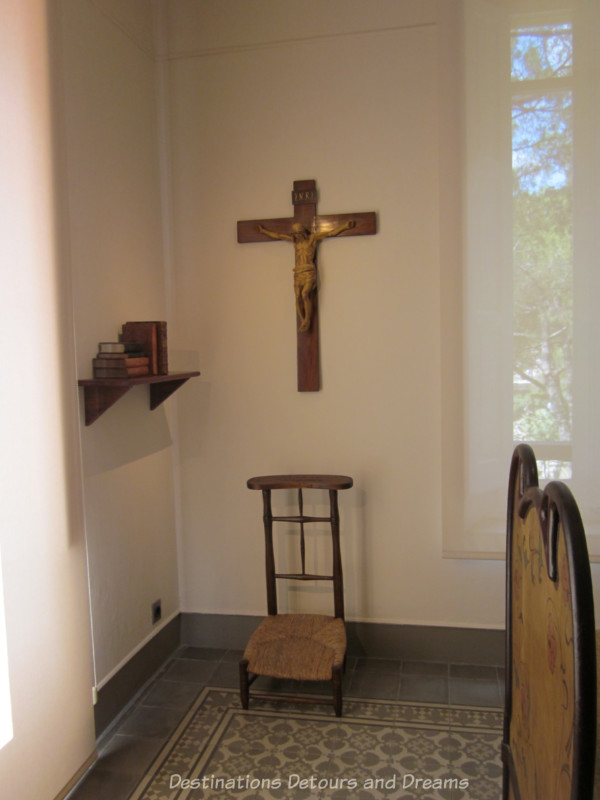 Austere wood chair with cane seat under a crucifix as part of room's prayer area 