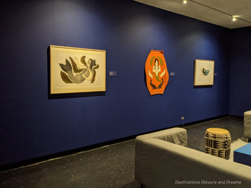 Art gallery space with dark blue walls displaying Inuit art work at the Winnipeg Art Gallery