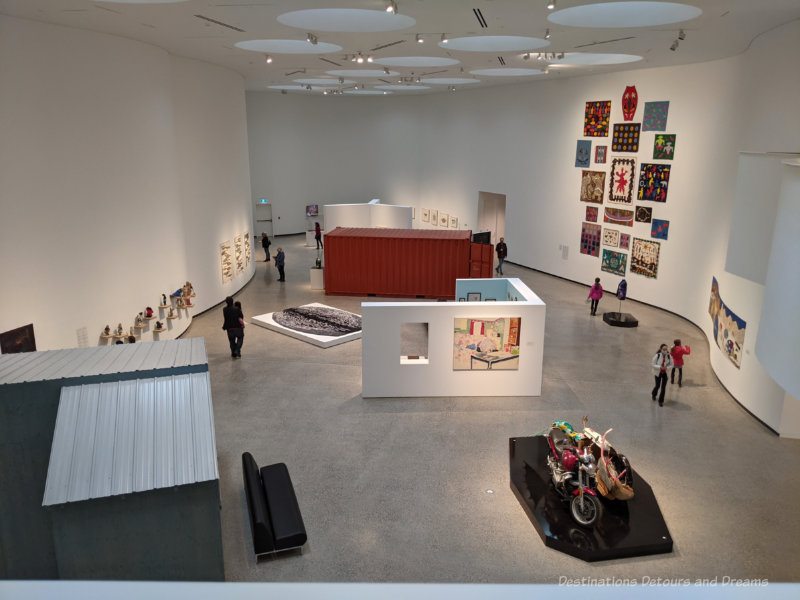 Looking into a two-story sky-lit white walled art gallery space from a mezzanine gallery at Qaumajuq