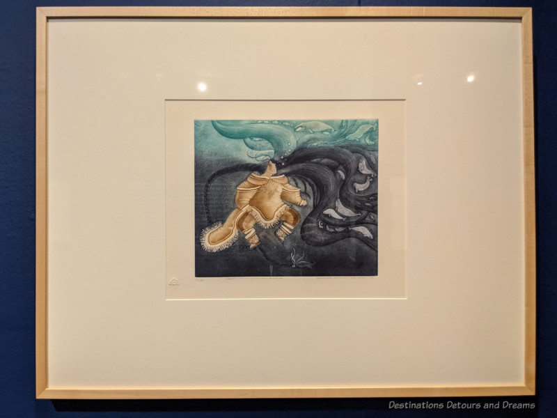Painting of a figure in seal skin under swirls of black and teal water tells a story about the Inuit sea spirit
