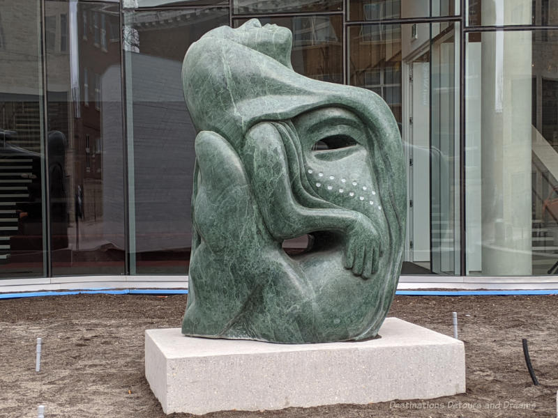 Green marble sculpture by Inuit artists Goota Ashoona is a sytlized version of Sedna, the Inuit sea spirit, and the tattooed face of a lady.