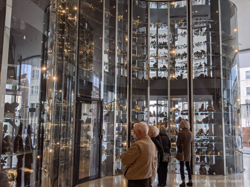 People viewing Inuit carvings inside behind the glass walls of the Visible Vault at Qaumajuq