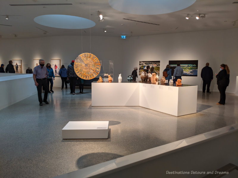 A mezzanine level art gallery with a central table of Inuit carvings and art on the walls