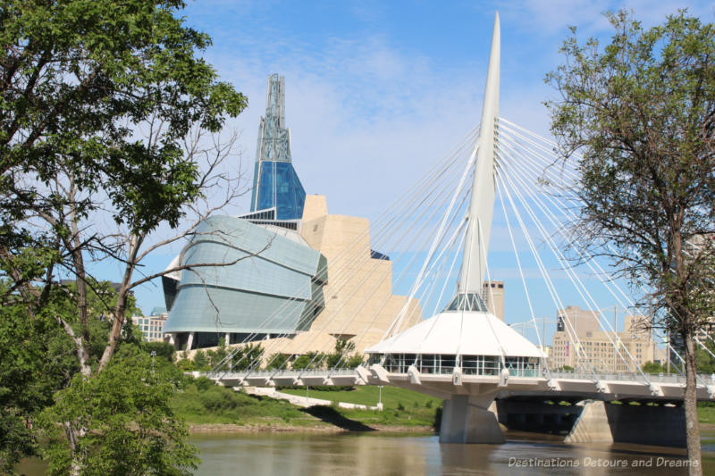 The granite wall, glass paneled wing, and tower of the Canadian Museum for Human Rights as view from across the river