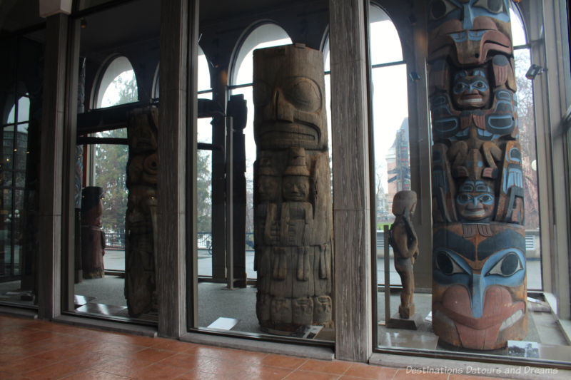Totem poles in a glass enclosure at the entrance to the Royal BC Museum