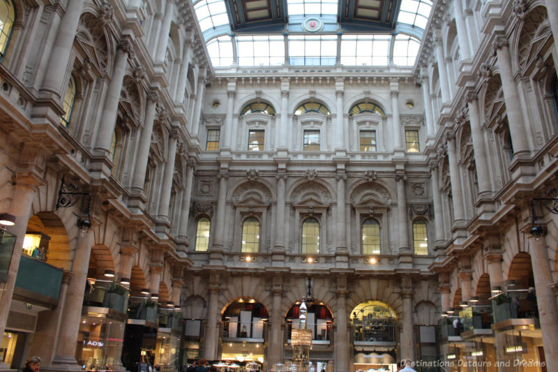 Courtyard inside the Royal Exchange building surrounded by three stories of ornate brickwork and topped with a glass ceiling