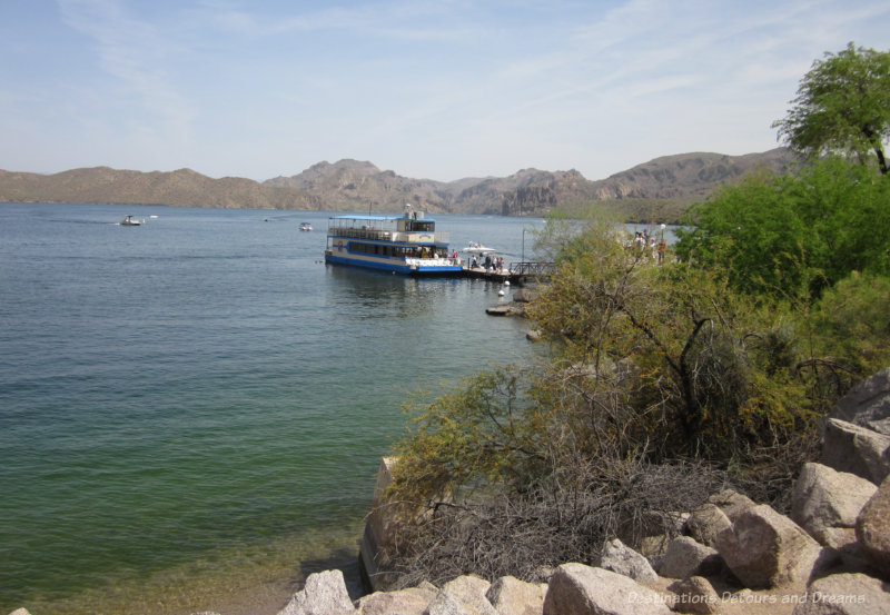 Two level cruising boat docked at Saguaro Lake surrounded by mountains