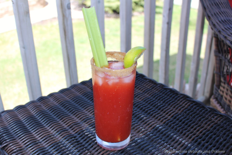 A glass containing a Caesar cocktail with a stalk of celery and a slice of lime
