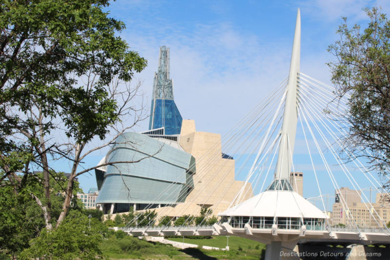 View of the exterior of the Canadian Museum for Human Rights showing granite wall on one side, the wings of glass on the other, and the Tower of Hope rising above both