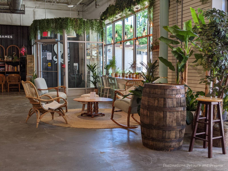 Seating area in Kilter Brewing taproom featuring arms chairs around a round coffee and counter seating at the large windows