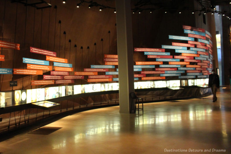 Wall of placards with interactive screens below them to show a human rights timeline at CMHR
