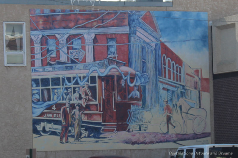 A mural in shades of red and blue showing a 1911 scene when Moose Jaw street car took its first run