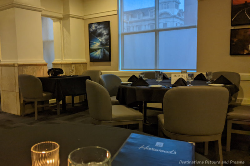 Tables in a fine dining restaurant with black tablecloths and gold upholstered chairs