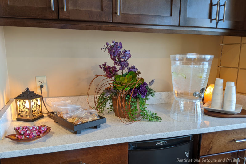 Water and snacks on a counter beside a floral arrangement